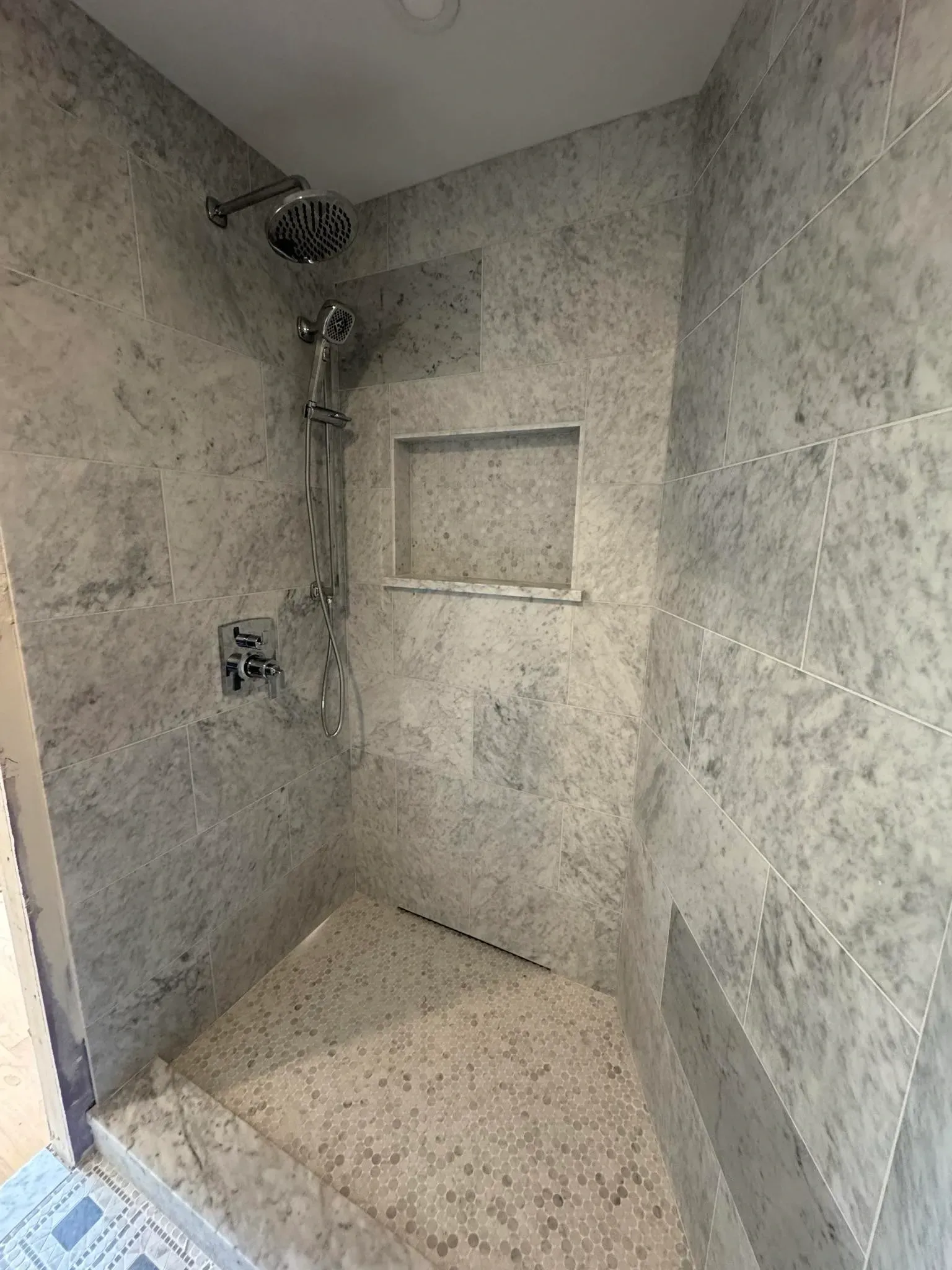 A bathroom with a walk in shower and a shower head.