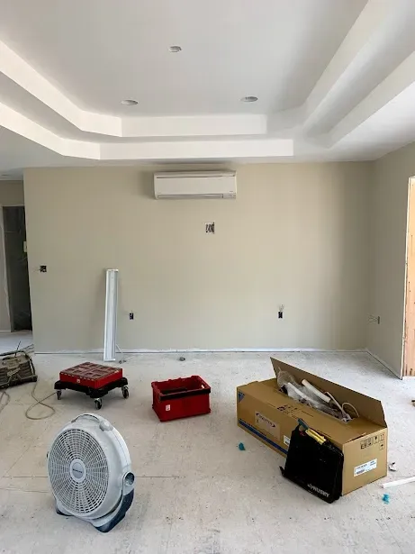 An empty room with a fan and boxes on the floor