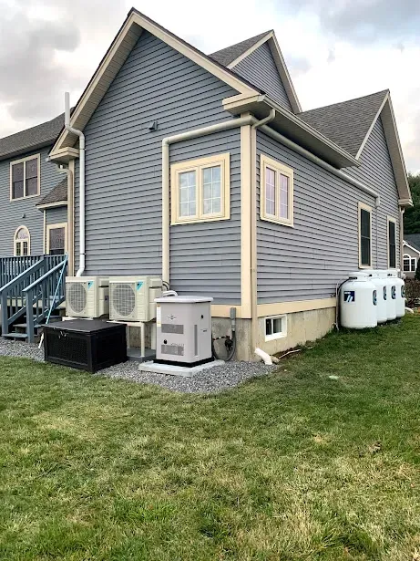 A house with a lot of windows and a generator in the backyard.
