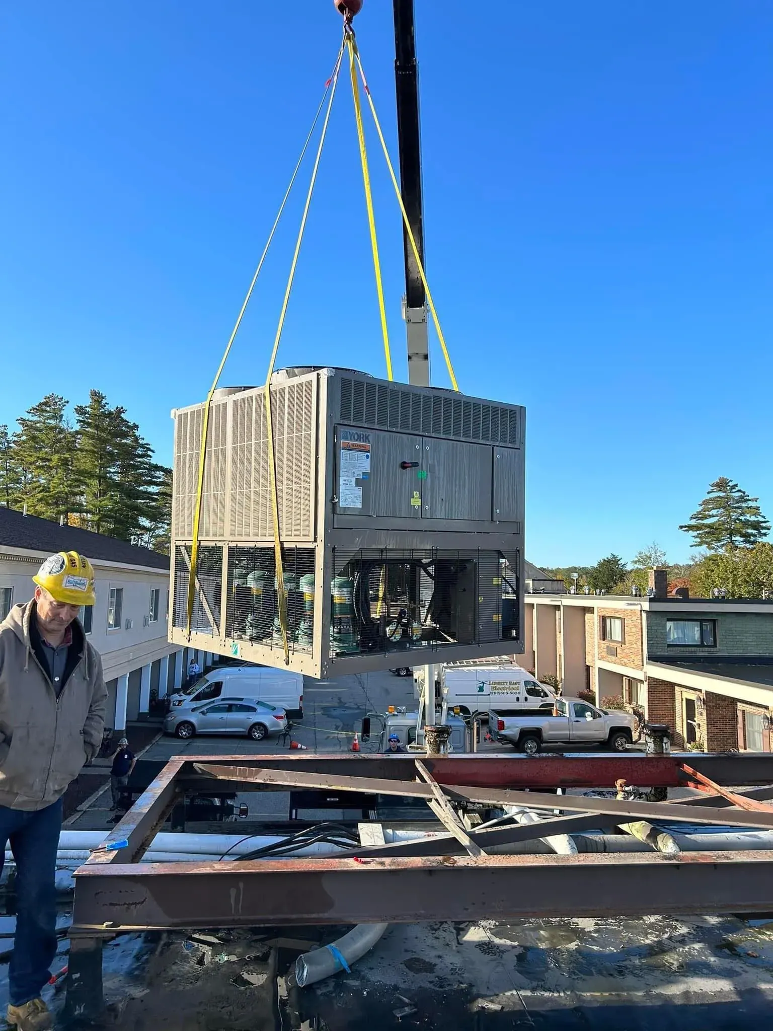 A man is standing next to a crane that is lifting a building.