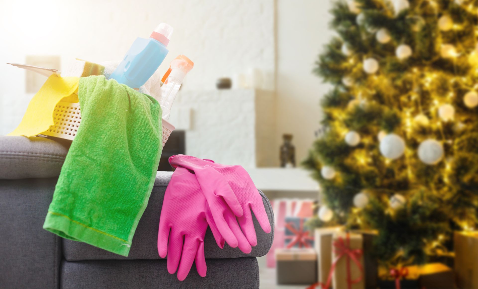 Cleaning supplies and gloves on a cart, with a decorated Christmas tree blurred in the background.