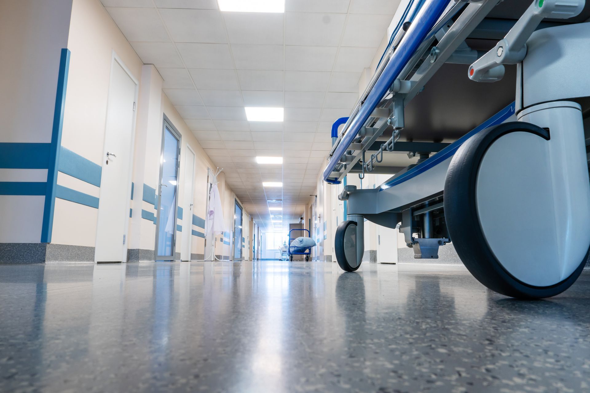 Hospital corridor with a stretcher cart in the foreground and bright overhead lights