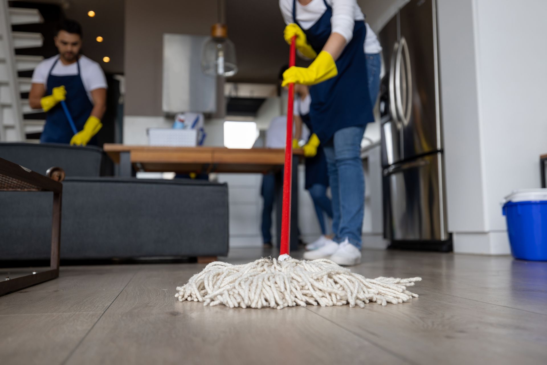 Person mopping a kitchen floor with a red mop in a modern apartment