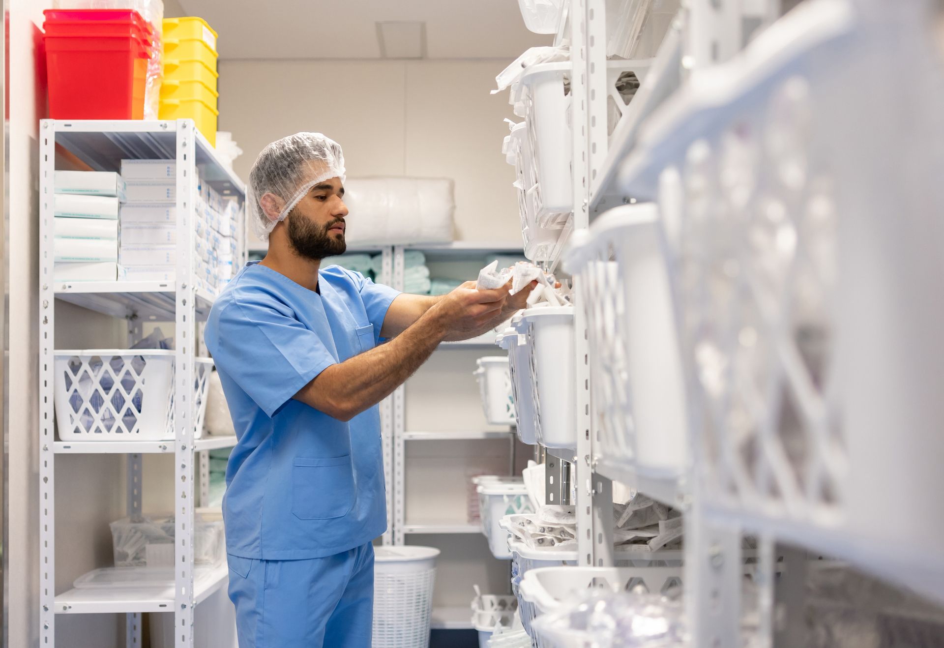 Worker in blue scrubs stocking shelves in a clean storage room