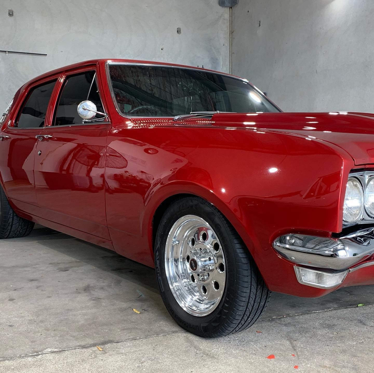 Red vintage car with chrome wheels parked in a garage — Tim Kratzke Detailing in Pialba, QLD