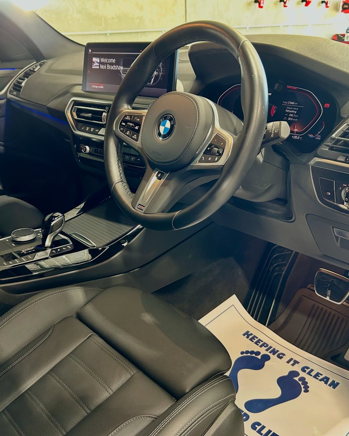 Interior of a BMW car; black leather seats, steering wheel, dashboard, and a foot-cleaning mat — Tim Kratzke Detailing in Pialba, QLD