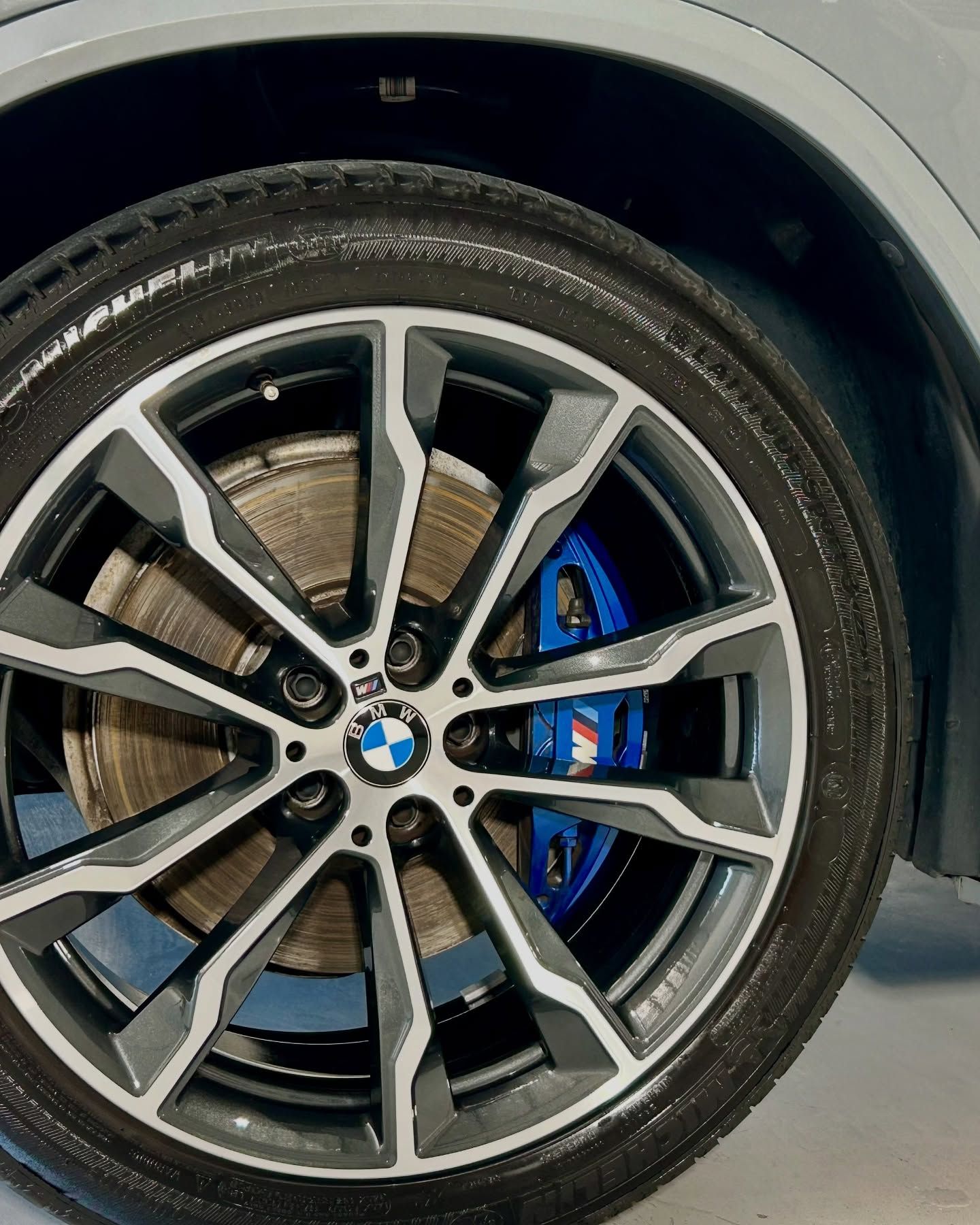 Close-up of a BMW car wheel with a blue brake caliper and a silver and grey rim — Tim Kratzke Detailing in Pialba, QLD
