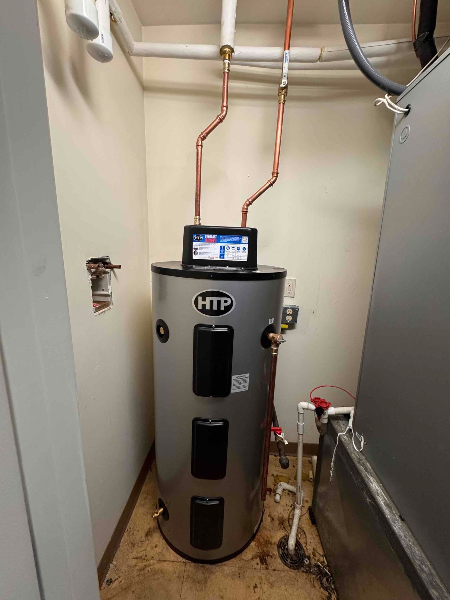 Rheem water heater in a utility closet with copper pipes and a wall-mounted control display