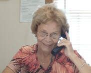Woman in a red patterned top talking on a phone in an office cubicle