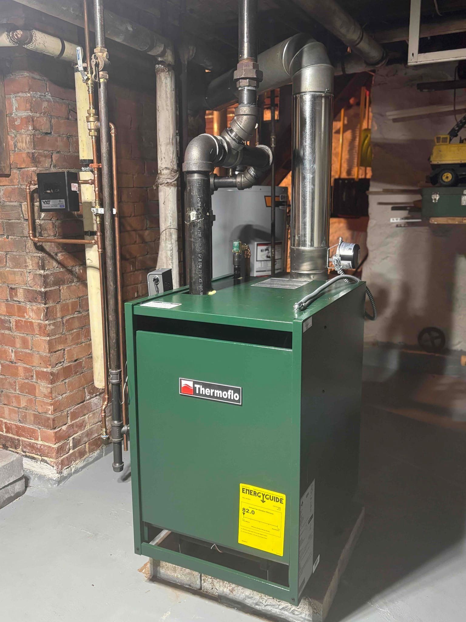 Green industrial boiler with pipes in a basement utility room