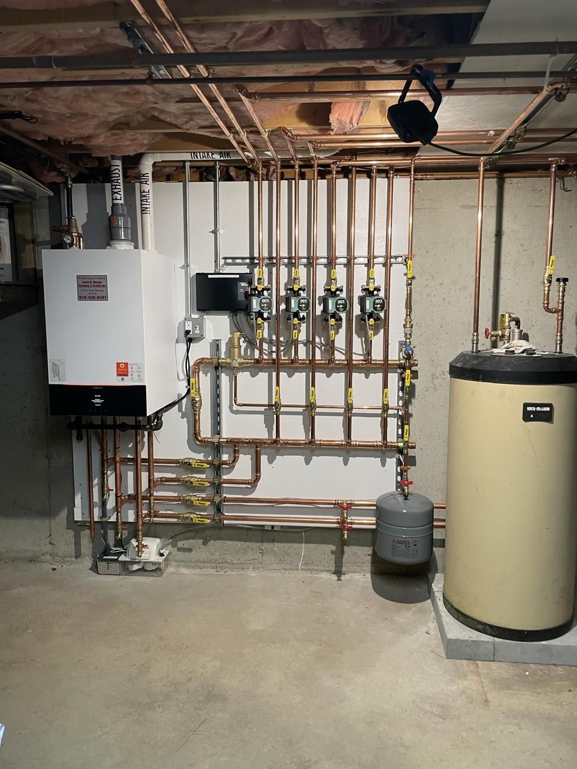 Basement mechanical room with boiler, water heater, and exposed copper plumbing.