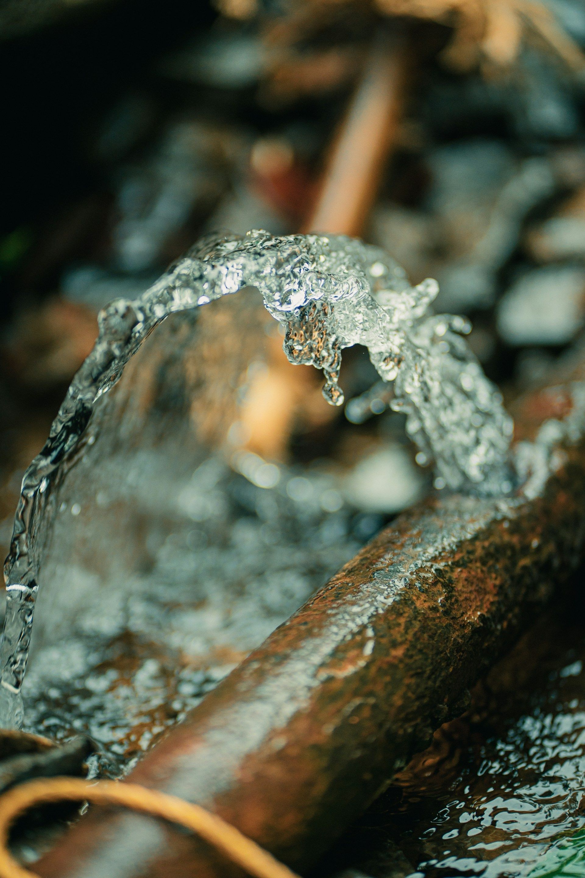 Rusty metal pipe with splashing water and ice in a wet, cold outdoor setting