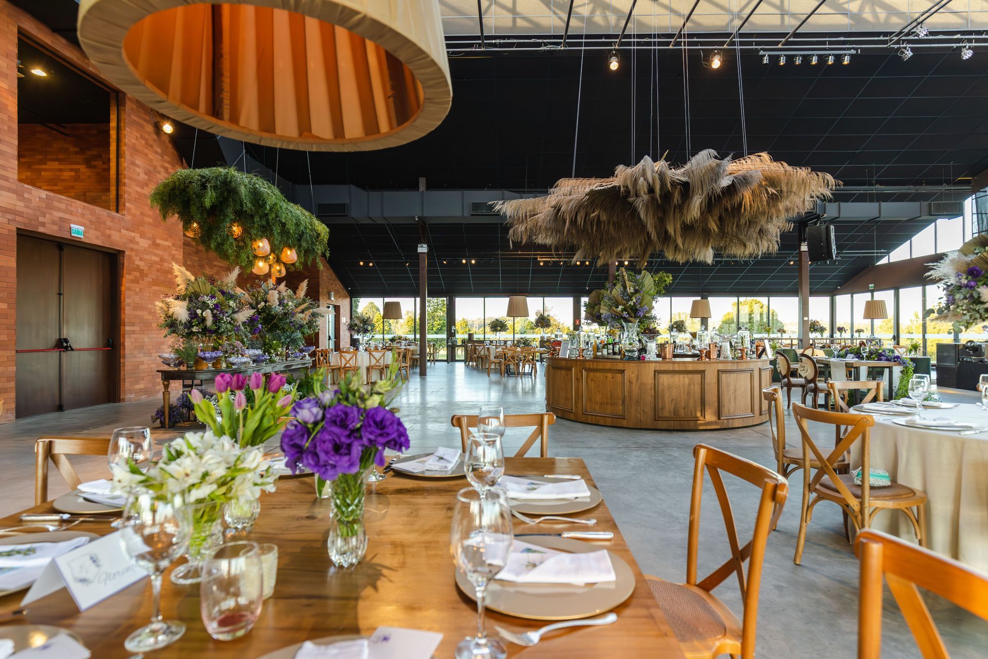 Elegante comedor de restaurante con mesas de madera, flores moradas y un espectacular centro de mesa colgante.