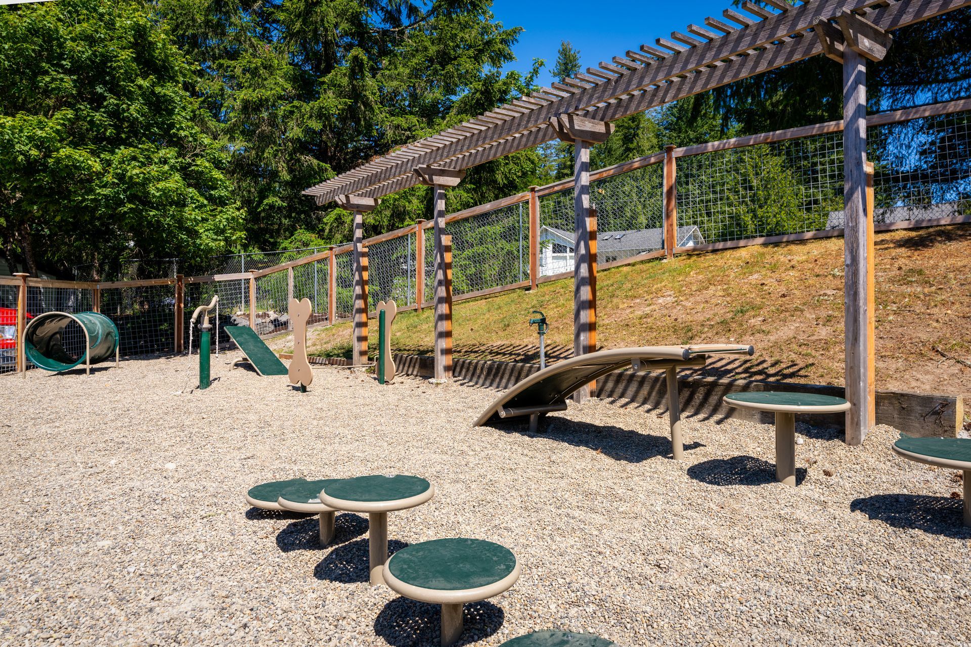 A playground with a slide , benches , and a pergola.