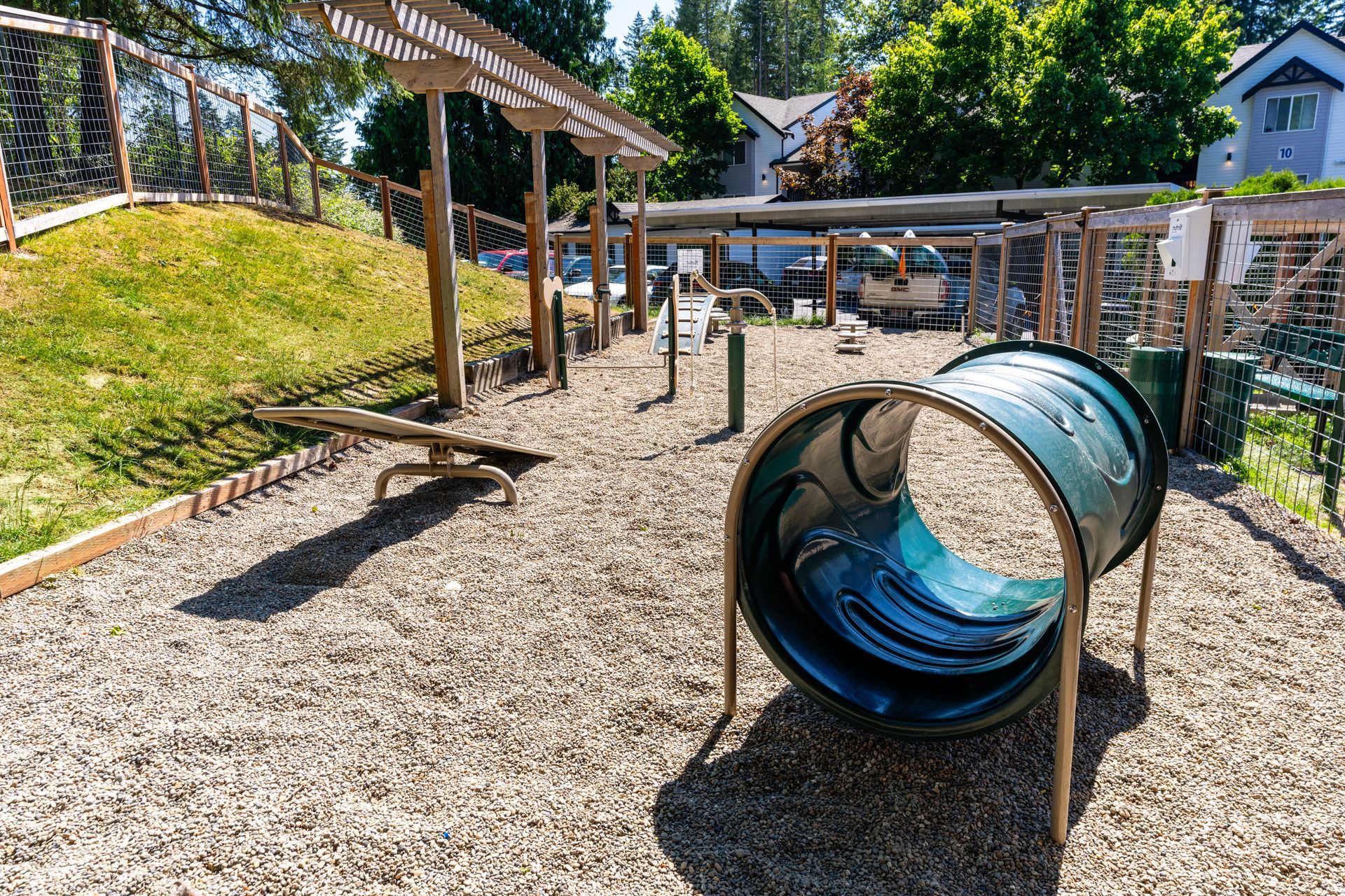 Dog park with agility equipment on wood chip ground.