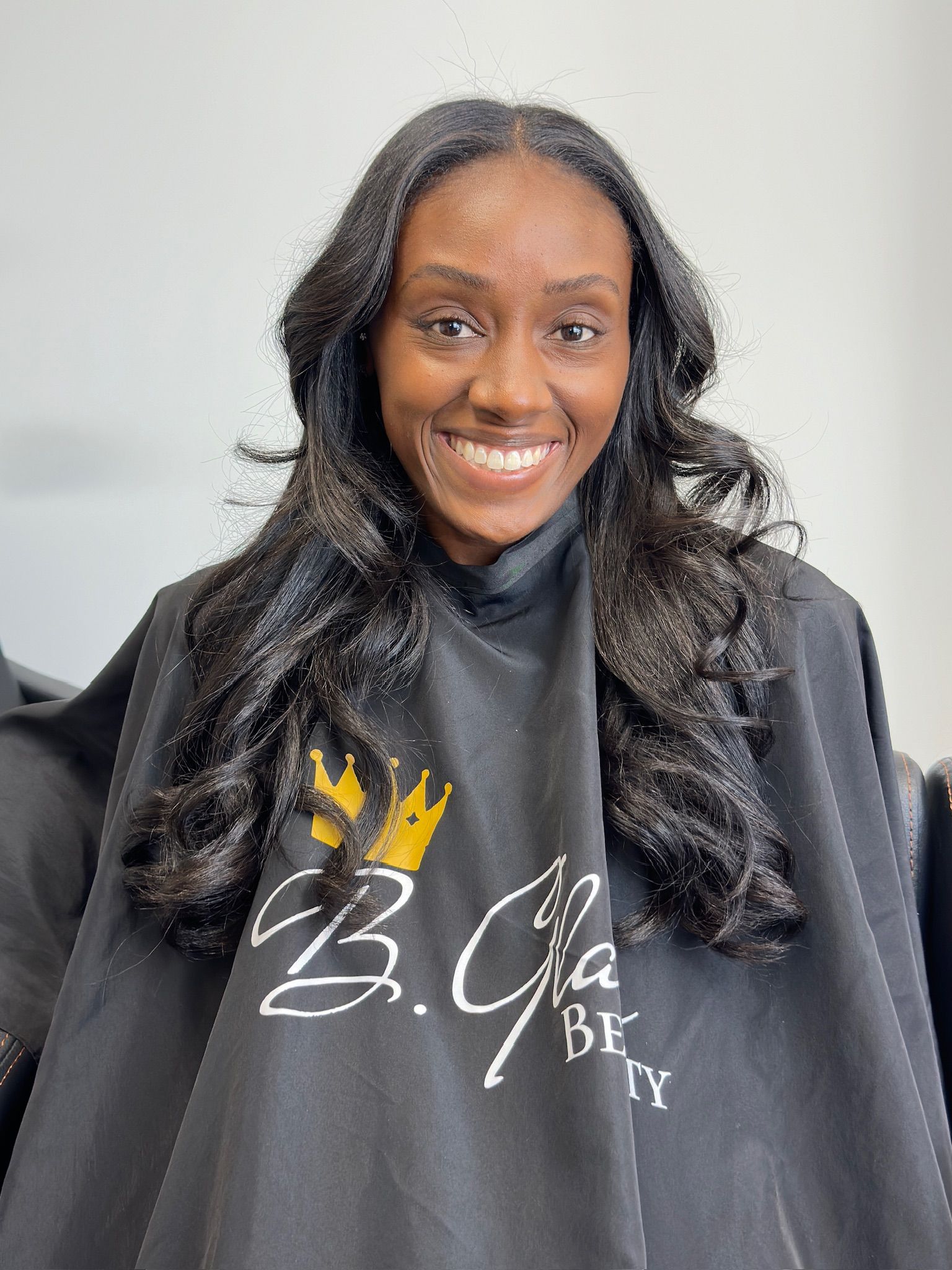 a young lady smiling in a salon with black hair framing her face
