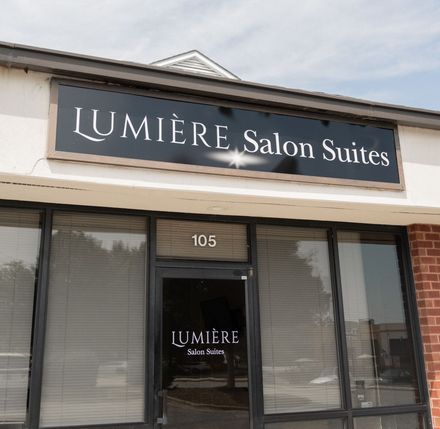 an image of the store front that B. Glam Beauty Salon is inside of.  There is a black sign that says Lumiere Salon Suites with glass windows and doors
