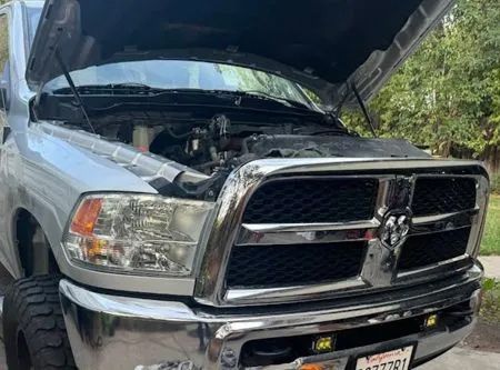 Silver Dodge Ram truck with hood open, parked outside.