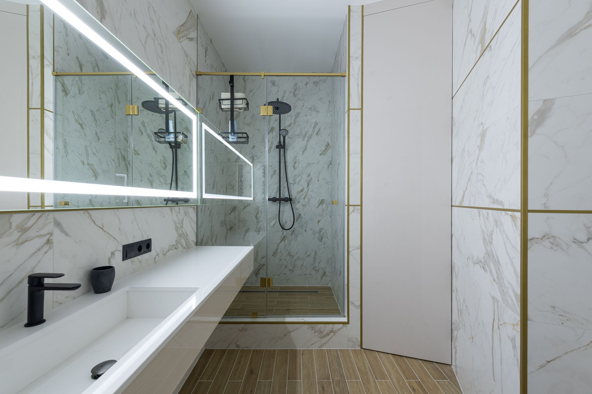 Modern bathroom with large mirror, double sink vanity, glass shower, and marble-patterned walls.