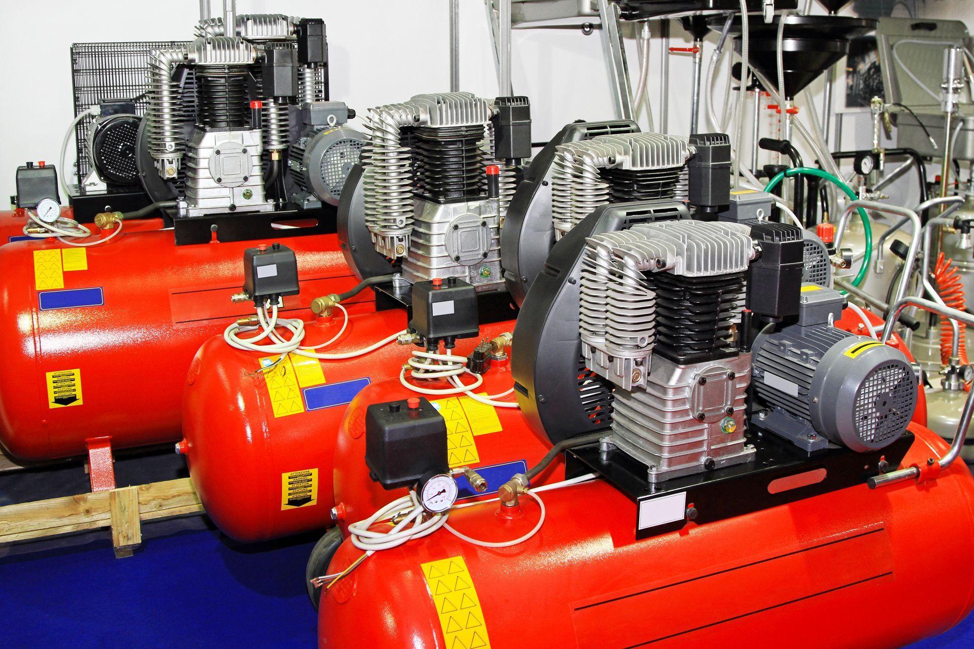 Red industrial air compressors with pressure gauges