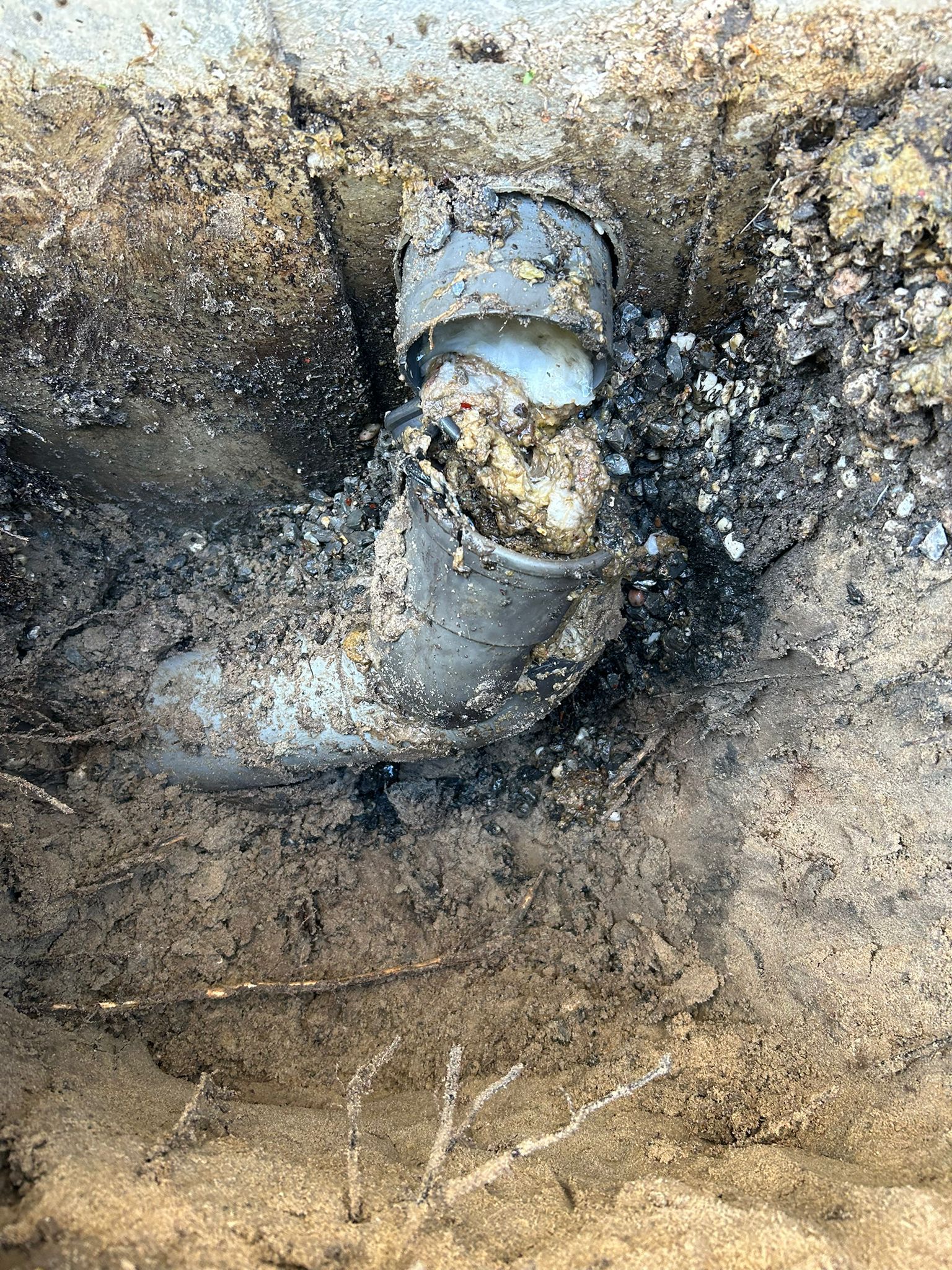 Close-up of a broken sewer pipe with debris/dirt coming out