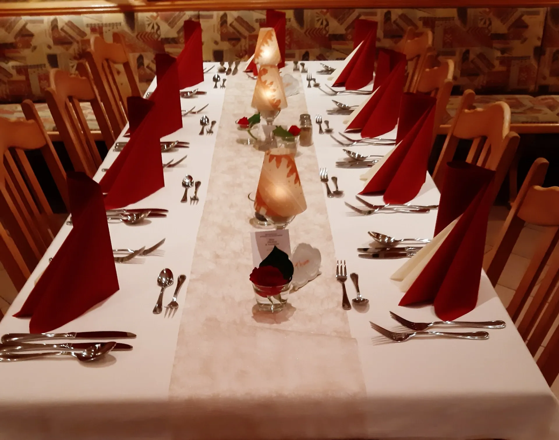 Ein langer Tisch mit roten Servietten und Kerzen darauf