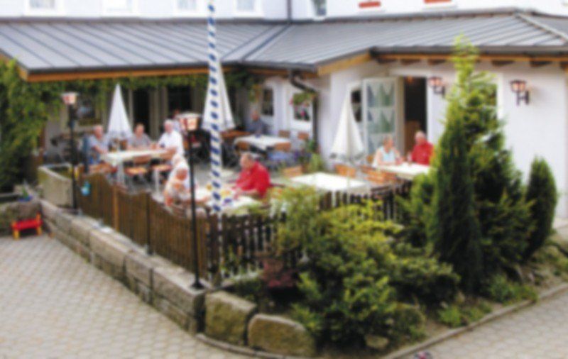 Eine Gruppe von Menschen sitzt an Tischen vor einem Restaurant