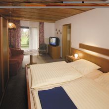 Ein Hotelzimmer mit zwei Betten, einem Fernseher und einer Couch.