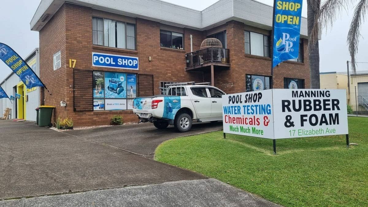A White Truck Is Parked In Front Of A Brick Building — Manning Pools, Rubber & Foam In Taree, NSW