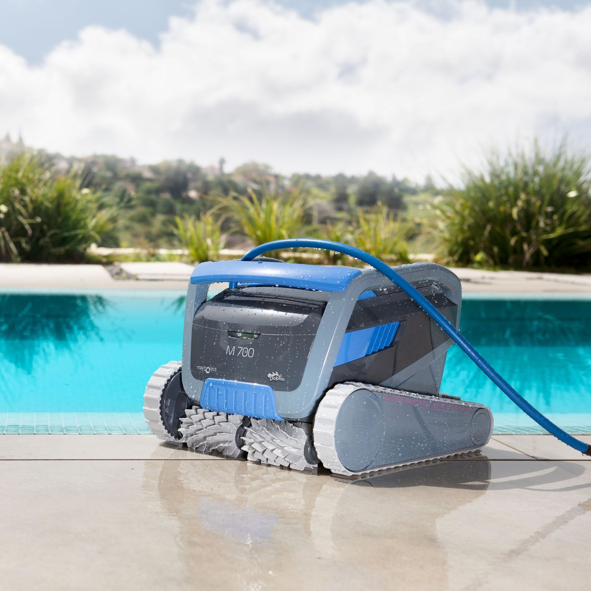 Blue Robotic Pool Cleaner on A Wet Patio Beside a Swimming Pool — Manning Pools, Rubber & Foam In Taree, NSW