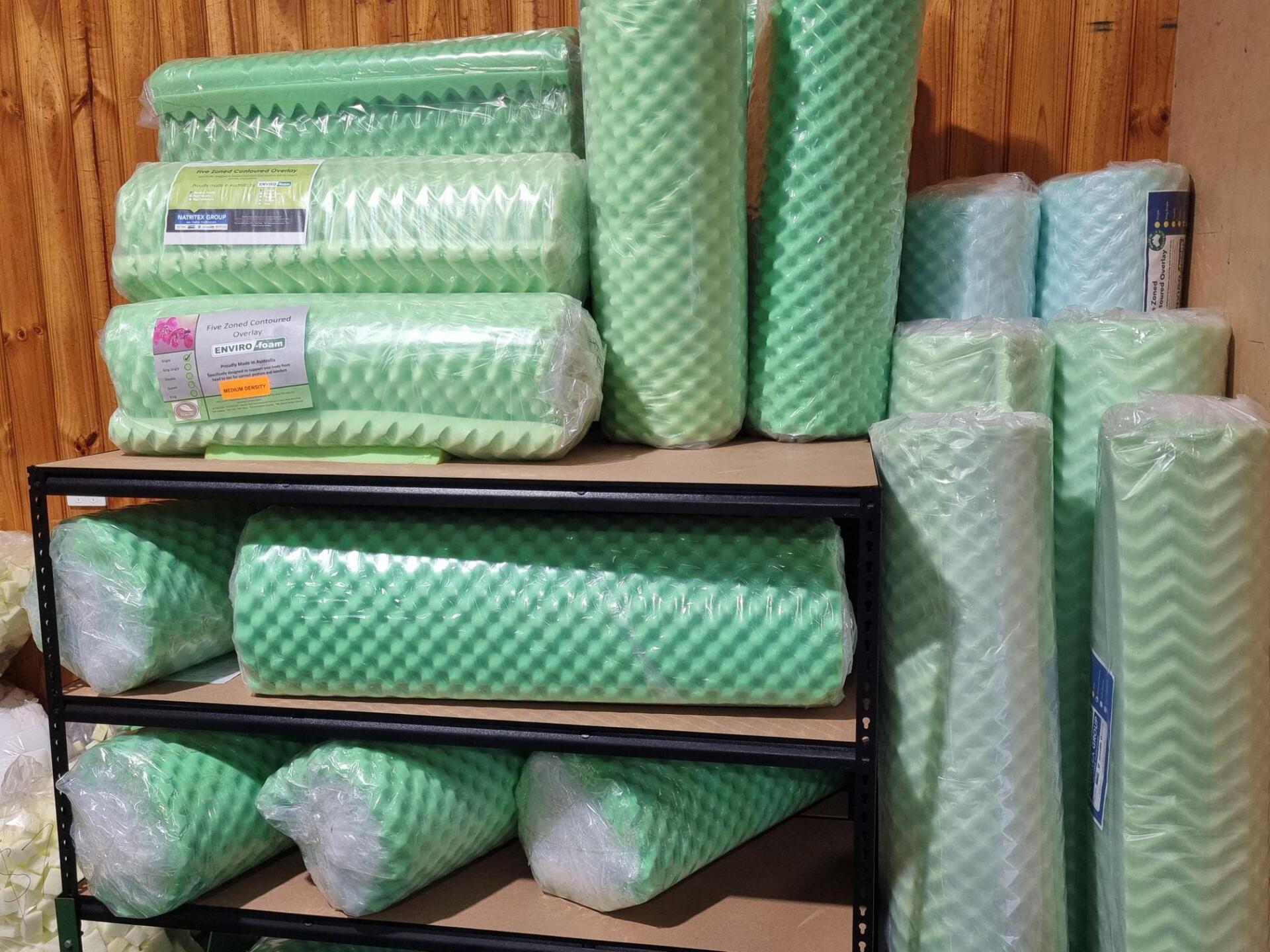 A Bunch Of Green Foam Rolls Are Stacked On Top Of Each Other On A Shelf — Manning Pools, Rubber & Foam In Taree, NSW