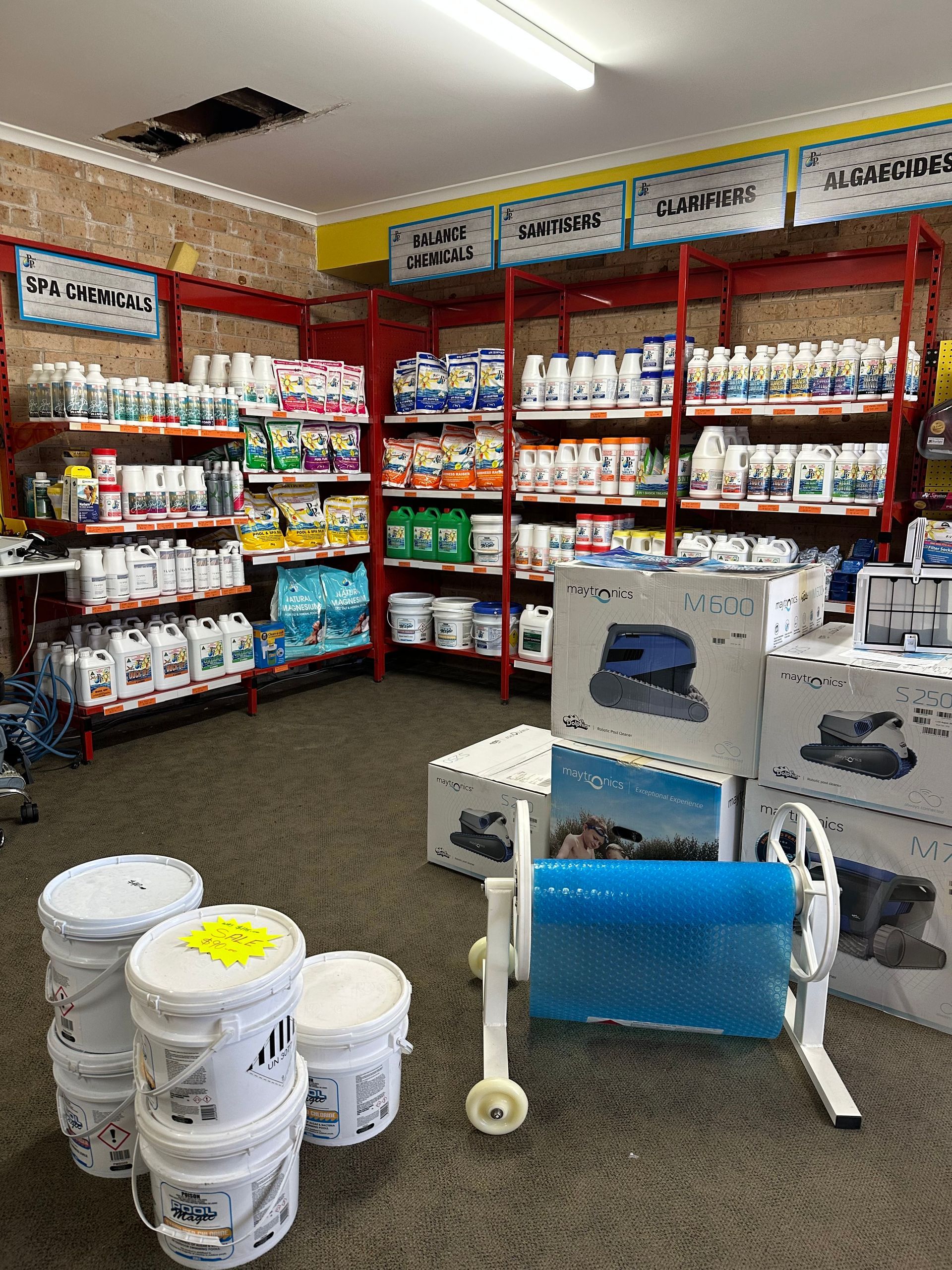 Pool supply store interior with shelves stocked with chemicals, pool cleaners, and accessories. Buckets in foreground. — Manning Pools, Rubber & Foam In Taree, NSW