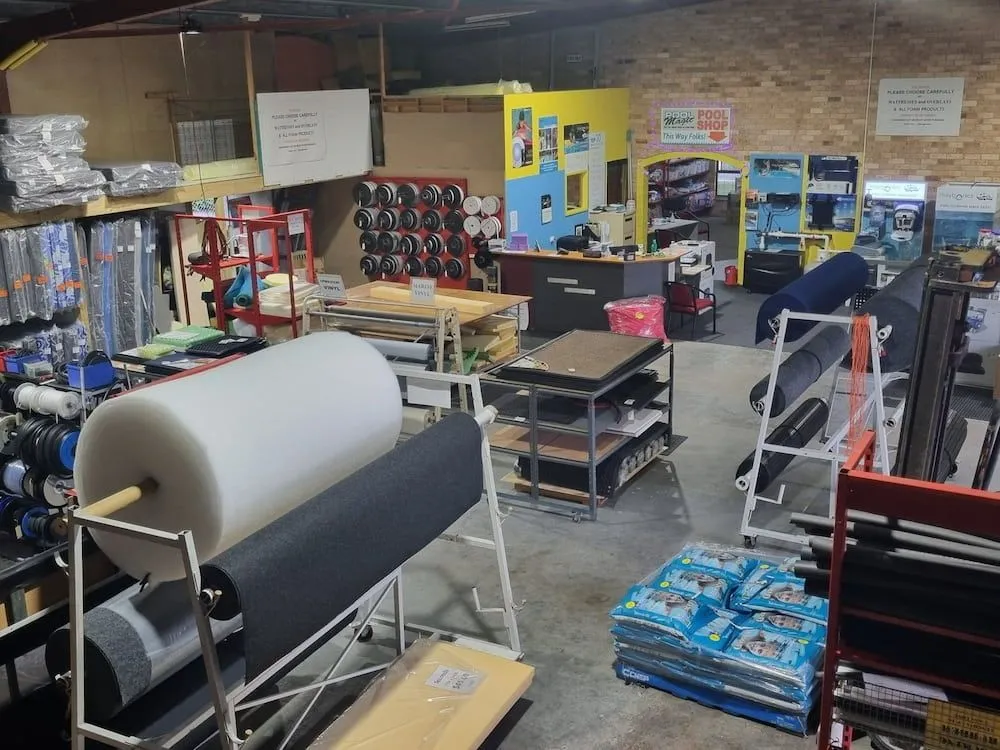 Interior of a warehouse with rolls of materials, shelves, and a checkout counter. — Manning Pools, Rubber & Foam In Taree, NSW