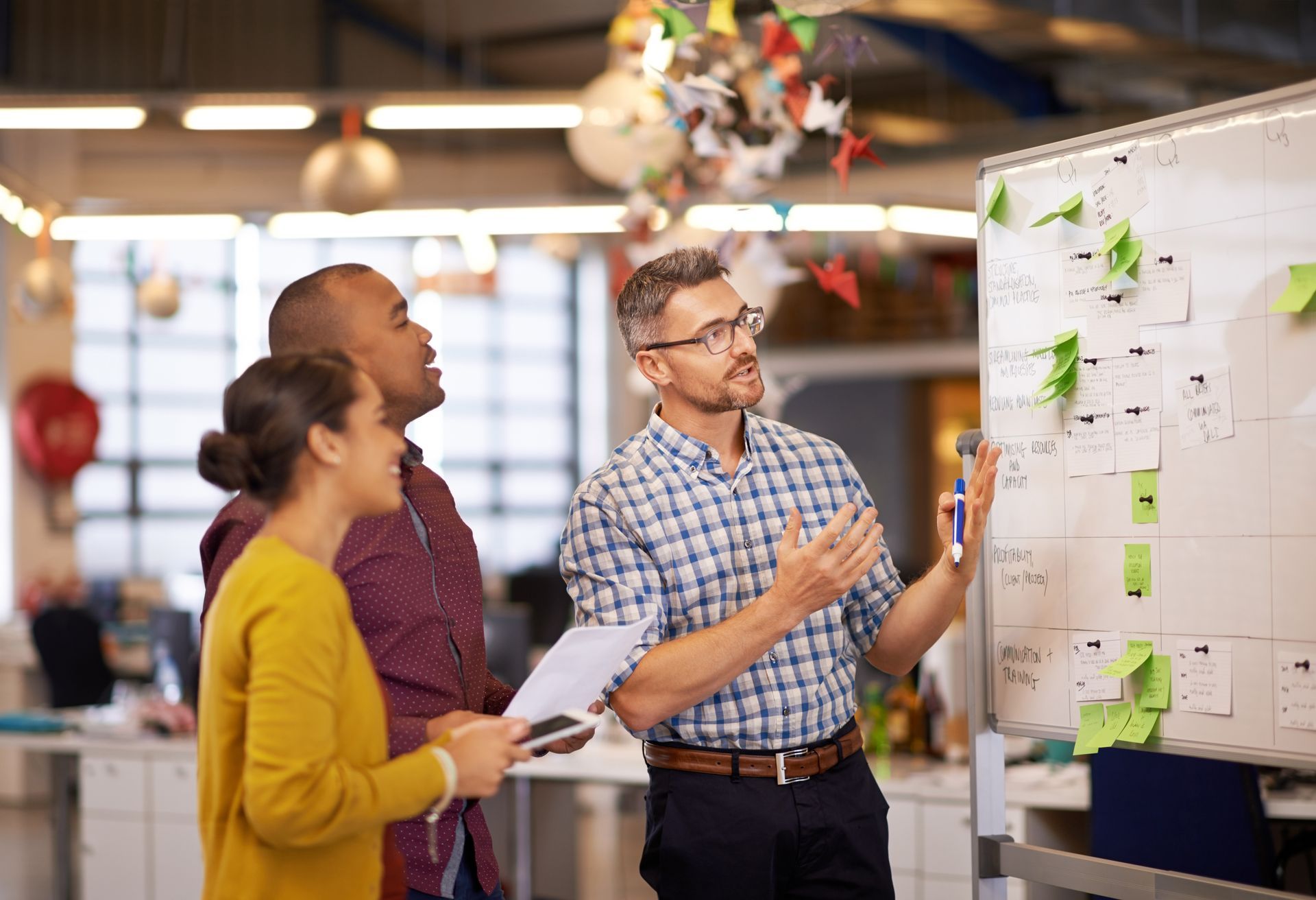 a group of people are looking at a whiteboard with sticky notes on it