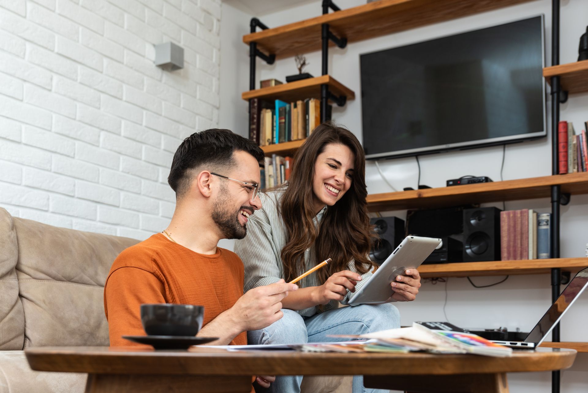 a man and a woman are sitting on a couch looking at a tablet