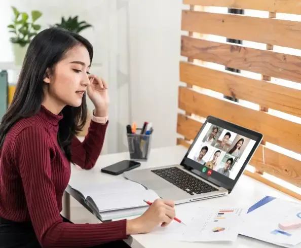 A woman is sitting at a desk using a laptop computer.