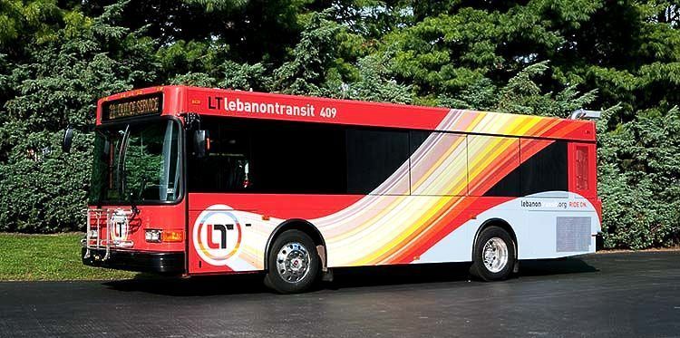 A red and white bus is parked on the side of the road