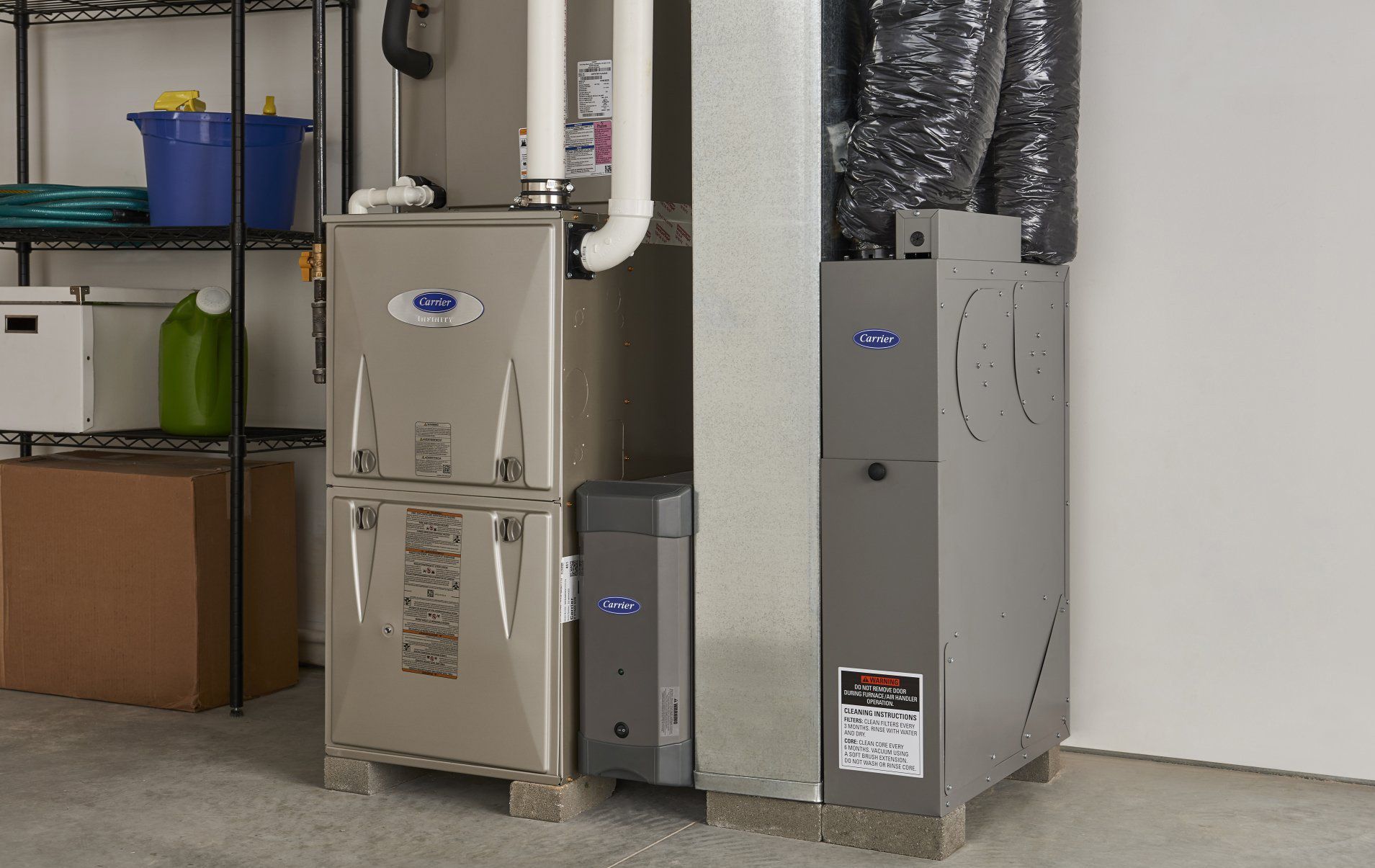 Two furnaces are sitting next to each other in a garage