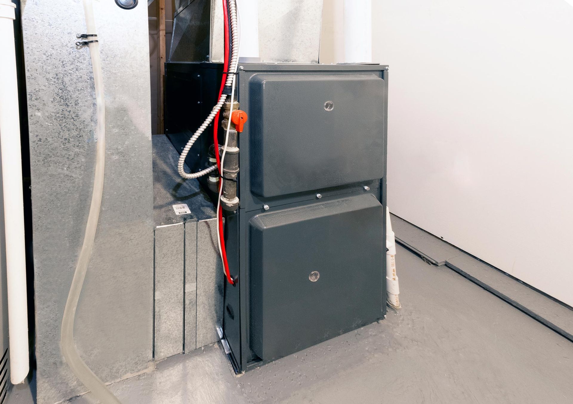 A large black furnace is sitting in a room next to a wall.