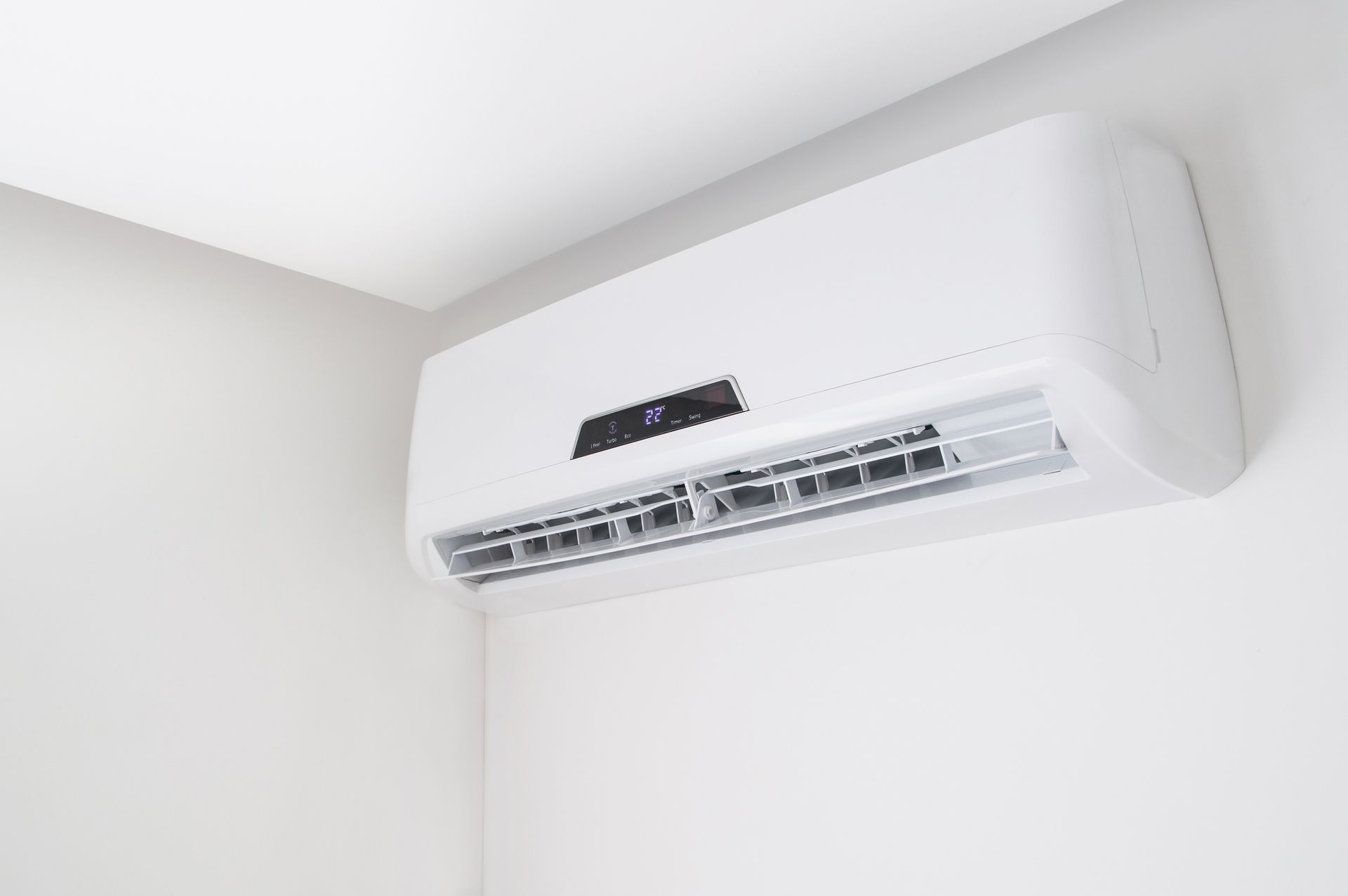 A white air conditioner is hanging from the ceiling in a room.