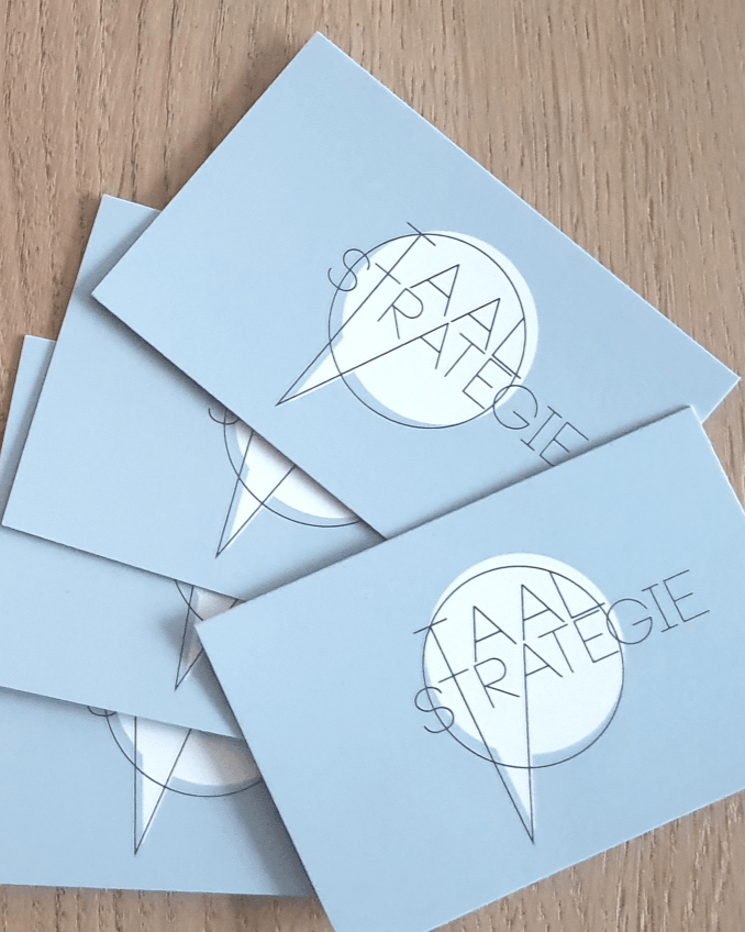 Stapel lichtblauwe visitekaartjes met een rond logo en puntige lijnen op een houten ondergrond.