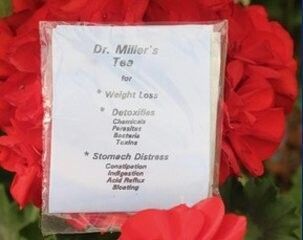 Herbal tea packages with pink flowers and green leaves, labeled for weight loss and stomach distress