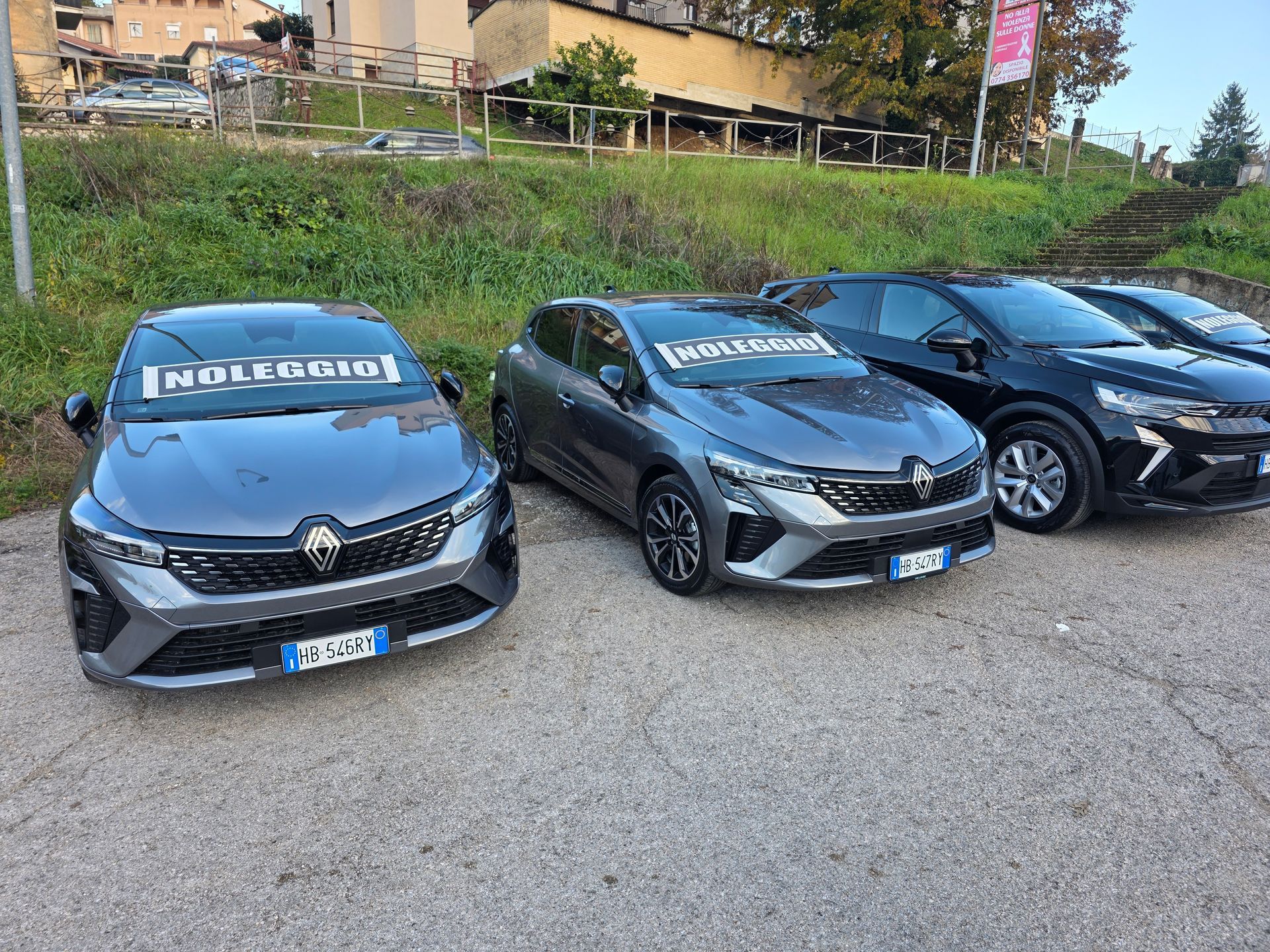 Tre persone esaminano una chiave dell'auto accanto a una berlina nera in una concessionaria