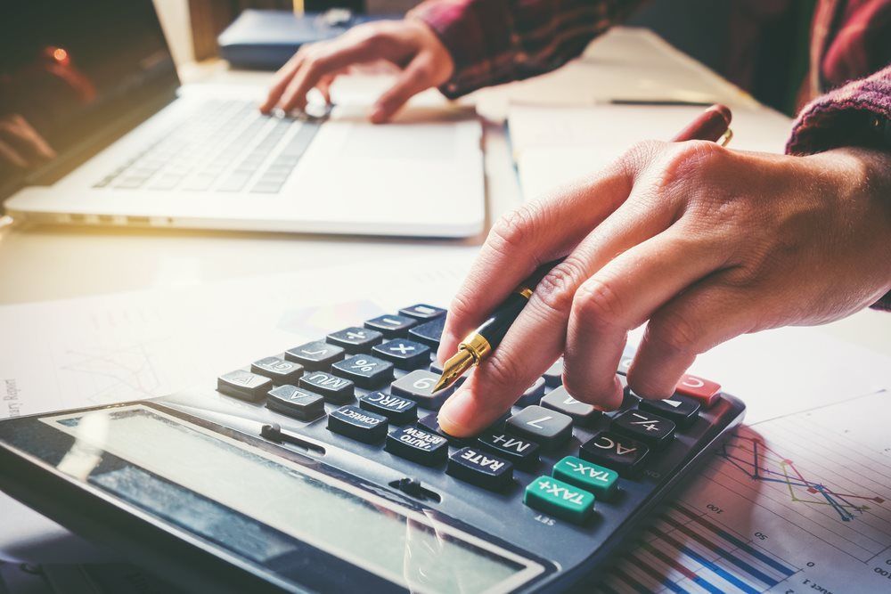 A Person is Typing on a Laptop While Using a Calculator — Repo Busters Wyong In Wyong, NSW