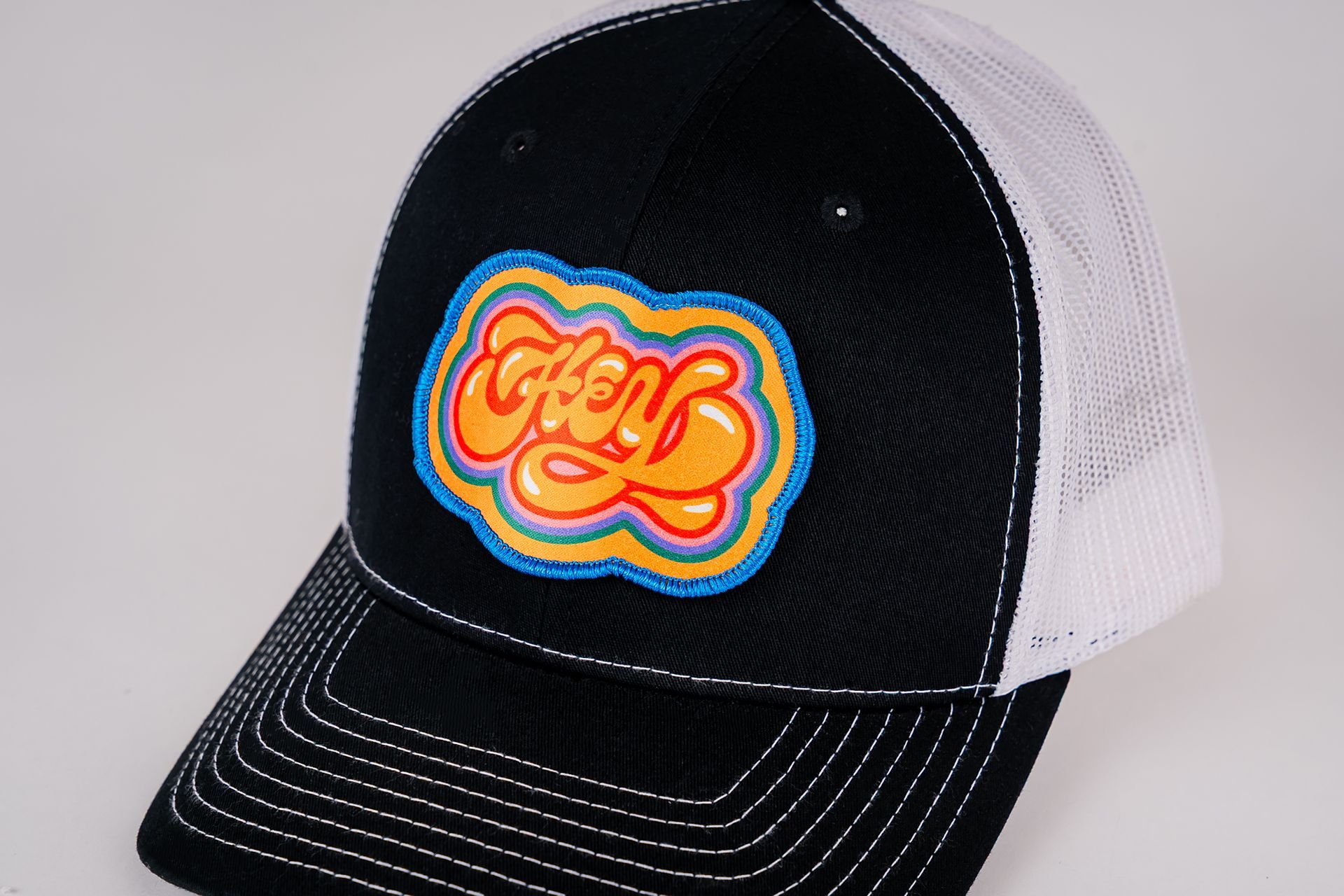 Black trucker hat with white mesh back and colorful