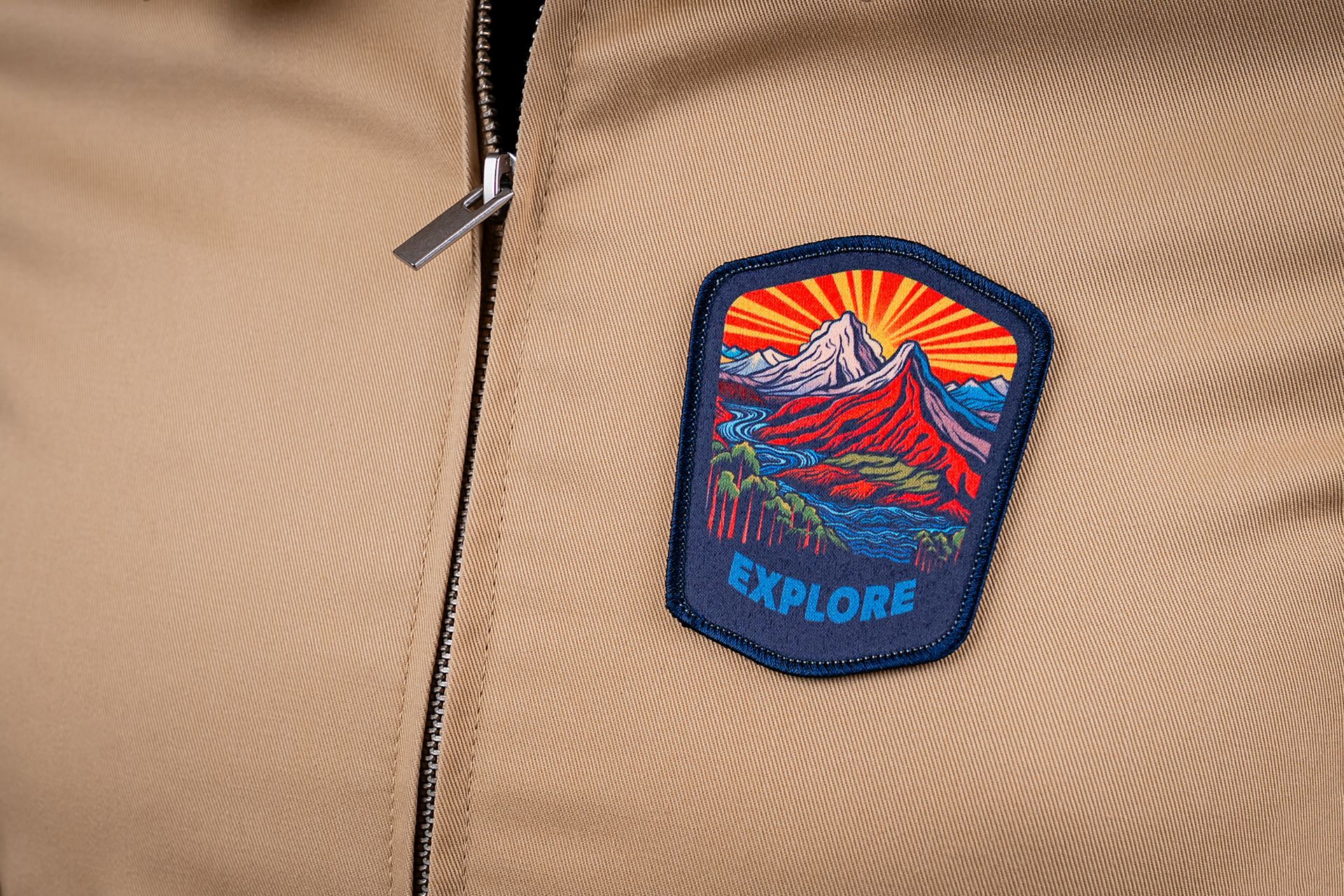 Tan jacket with a patch depicting a mountain range and the word