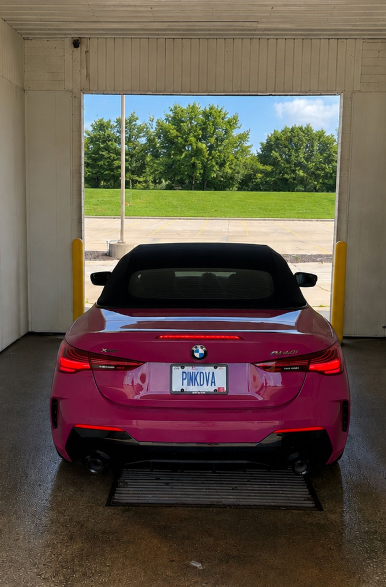 Red BMW sports car parked in a car wash bay, viewed from the rear.