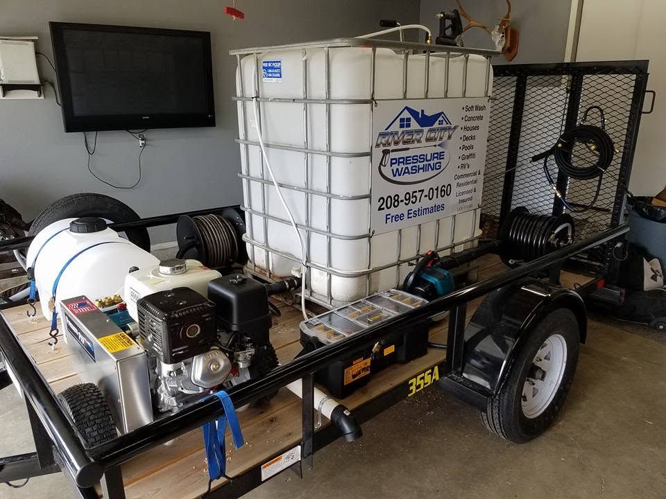 Trailer-mounted pressure washing unit with white water tank and black machinery in a garage