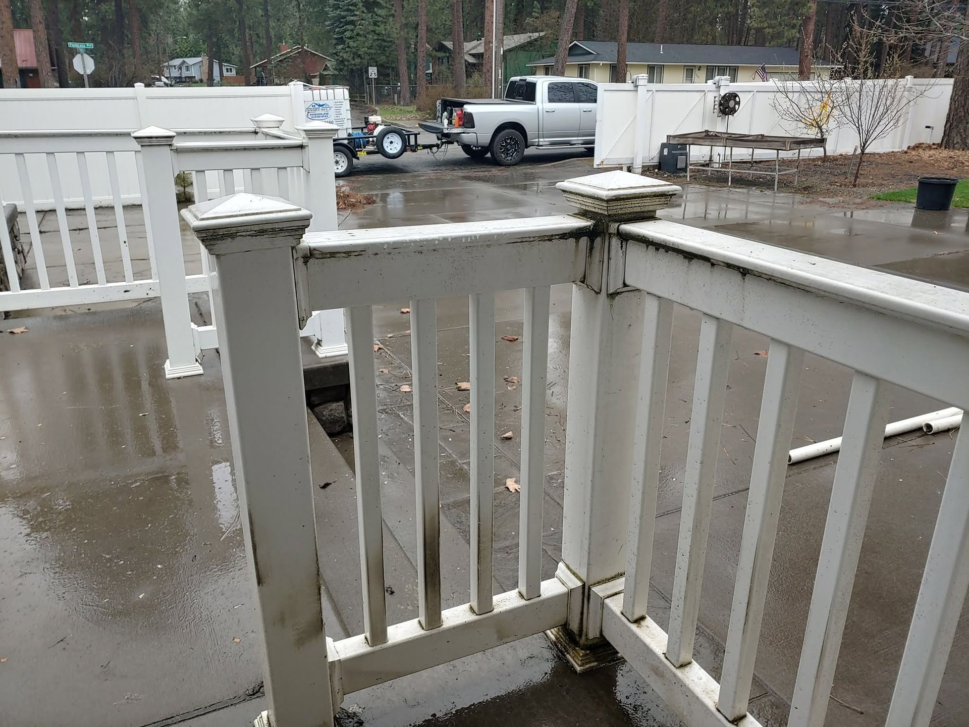 Snow-dusted white porch railing overlooking a wet residential street with parked vehicles.