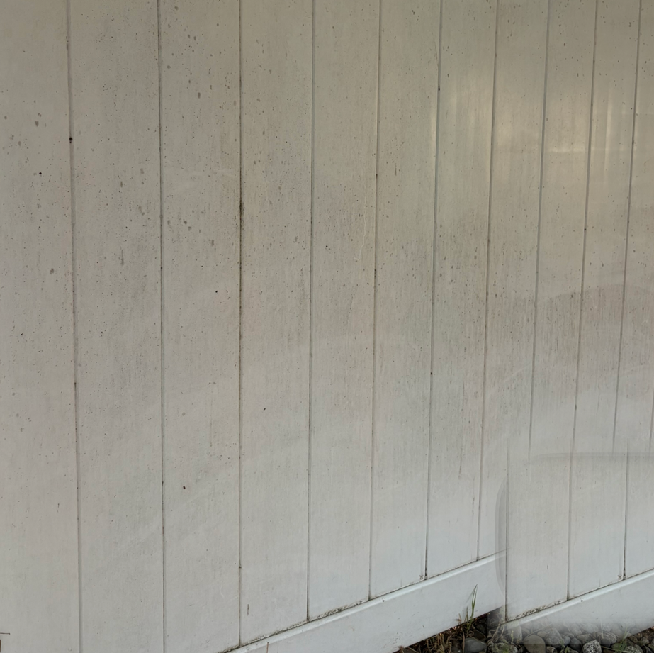 White paneled wooden wall with vertical slats and a small section of brick at the bottom right
